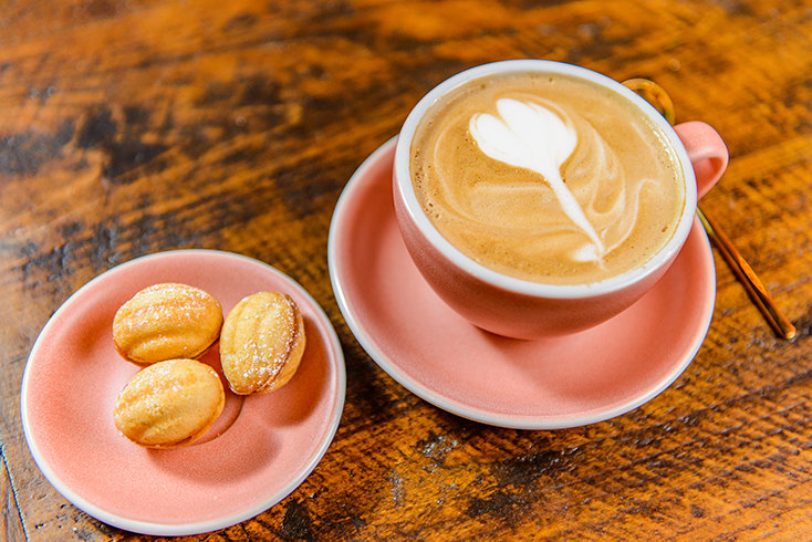 A latte and small nut pastries are served inside Nubo, where coffee, handmade desserts and fresh-baked goods are central to the café experience.