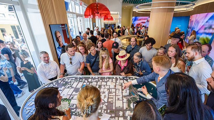 Guests gather around a detailed downtown Clearwater model, examining the building-by-building redevelopment now advancing along Cleveland Street.